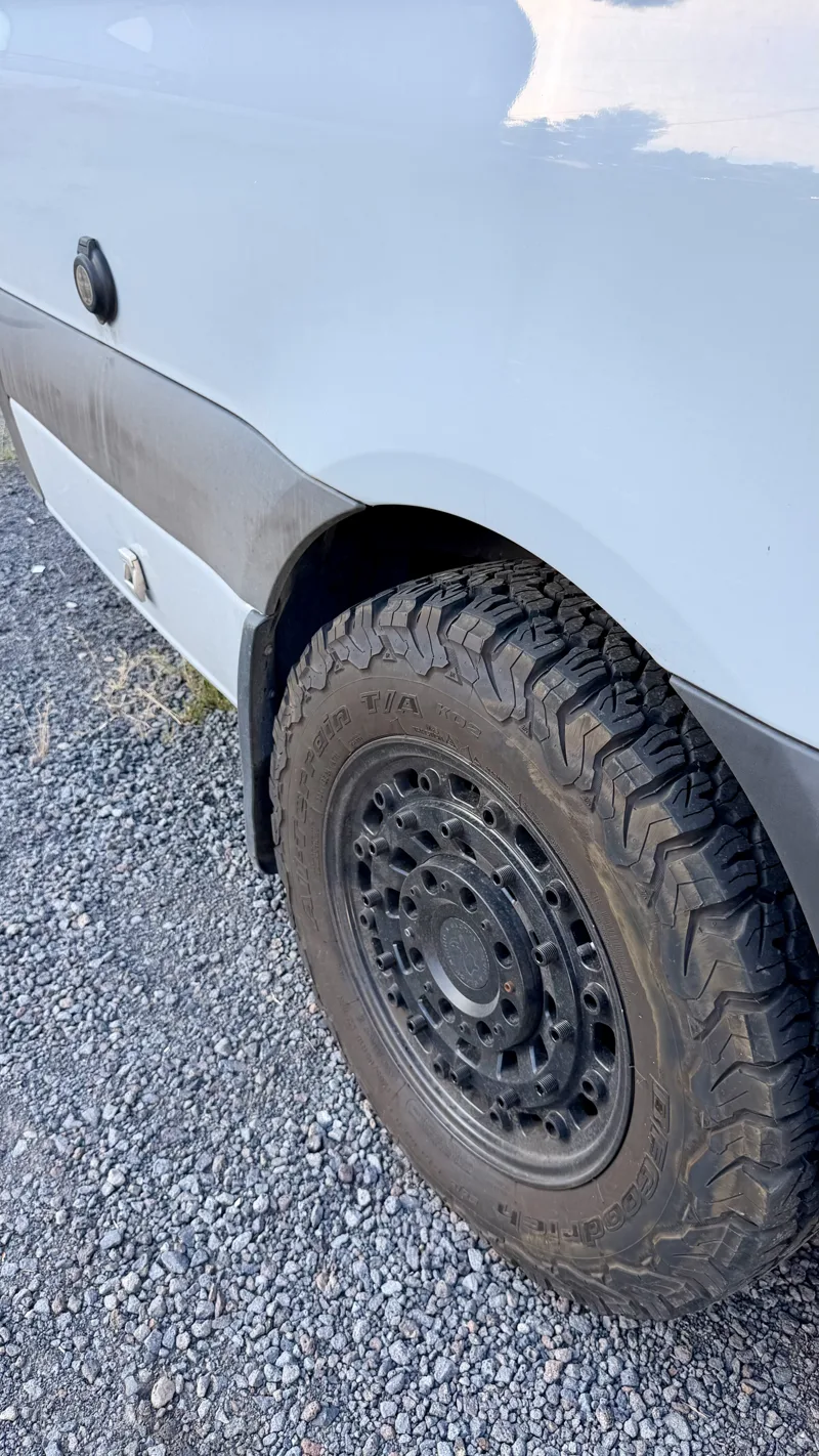 All-terrain tire and black wheel beside the van body
