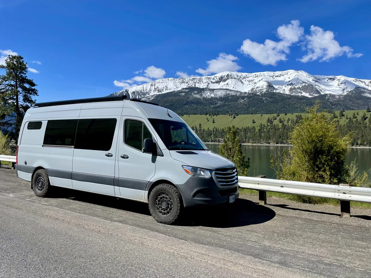Pebbles parked beside a lake with snowy mountains beyond