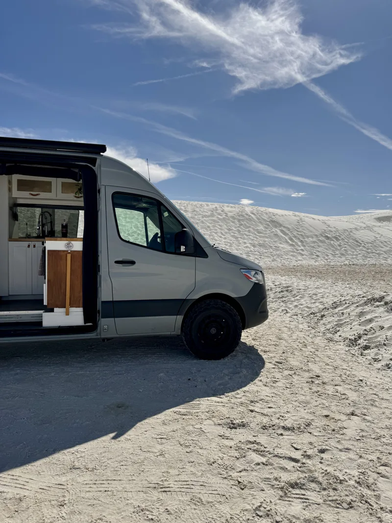 Pebbles’ front half and open door on white sand