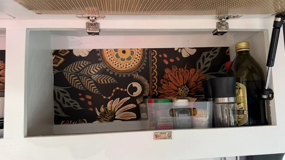 Right upper kitchen cabinet open with glasses and kitchen supplies