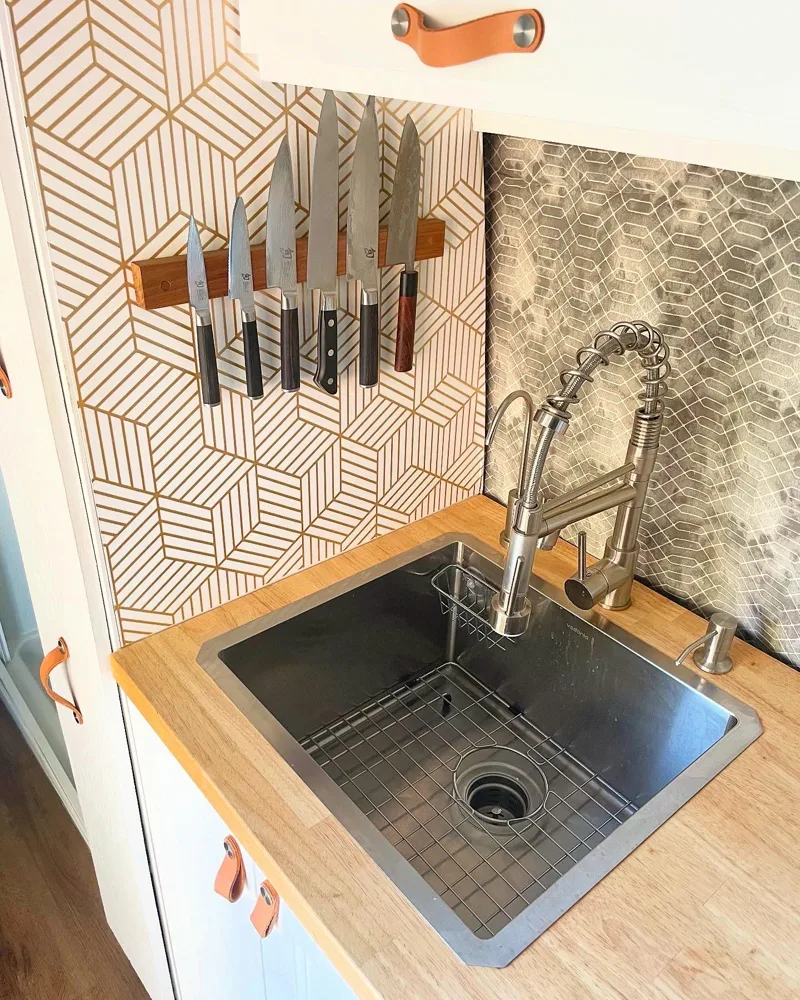 Kitchen sink, tiled backsplash, and magnetic knife rack