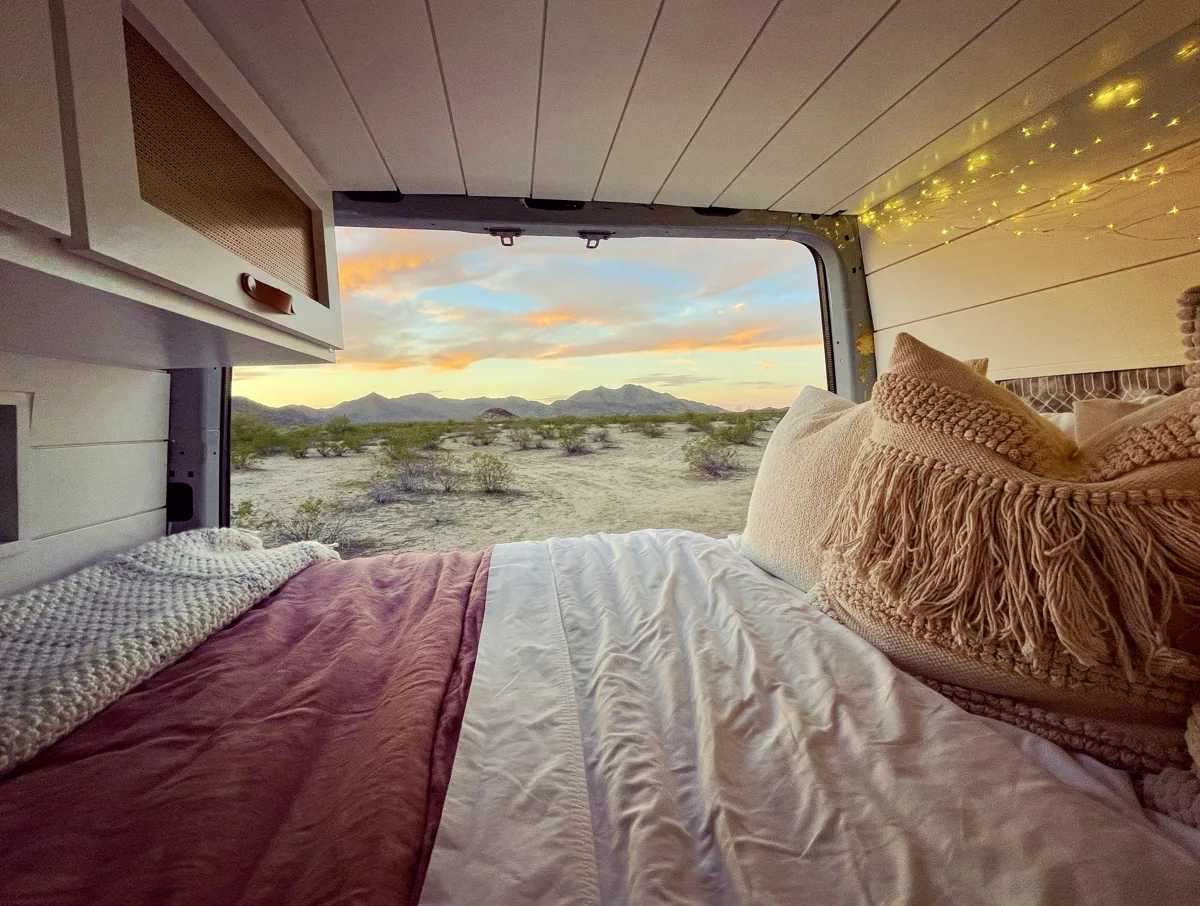 Pebbles’ bed made up beside a window at sunset